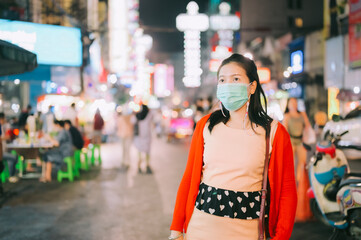 Young Asian tourist woman wearing mask for protection from corona virus outbreak in Chinatown at night