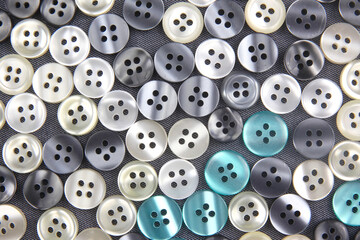 Obraz premium Plastic shiny buttons for clothes on a fabric background. Fashion and clothing. Factory industry