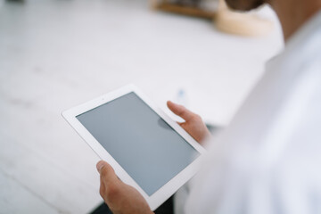 Unrecognizable person using tablet while sitting in room