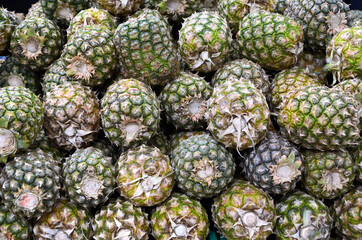 Fototapeta na wymiar Shelf with fresh whole pineapples at grocery market. Exotic fruits from organic farms. Merchandising fruit in market to attract buyers.