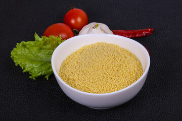 Raw couscous in the bowl served salad leaves, tomato and pepper