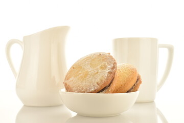 Several delicious biscotti shortbread cookies with white ceramic crockery, close-up, isolated on white.