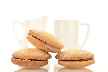 Several delicious biscotti shortbread cookies with white ceramic crockery, close-up, isolated on white.