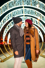 Romantic winter gaze of a Caucasian couple next to the christmas lights of the city, lifestyle