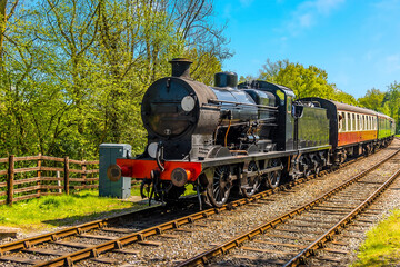 A steam train on a railway line in Sussex, UK on a sunny summer day