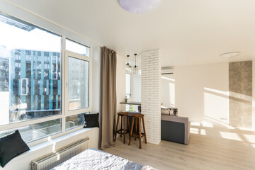 Open living room with couch, brick wall and small kitchen