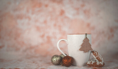 cup of coffee or tea with christmas tree toys on pink background