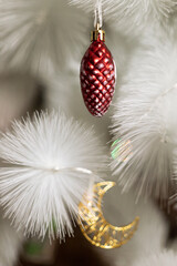 toys on a white christmas tree red pine cone and golden crescent