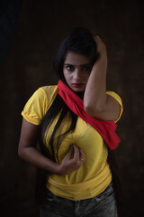 Studio portrait of a beautiful and young Indian Bengali female model in yellow tee shirt and jeans...