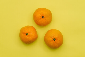 Tangerines isolated on a yellow background. Ripe fruits for health and immunity. Top view, flat lay