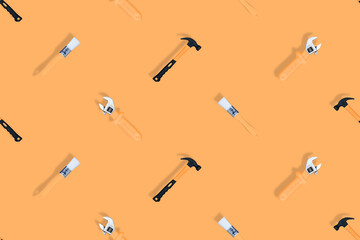 Obraz premium Tools seamless pattern. Tools: construction brushes, hammer, wrench on an orange background.