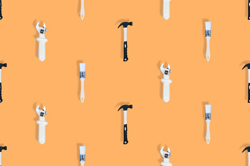 Tools seamless pattern. Tools: construction brushes, hammer, wrench on an orange background.