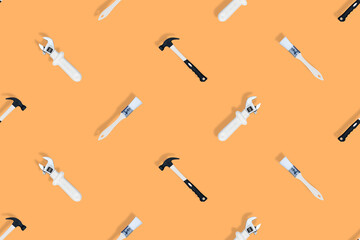 Tools seamless pattern. Tools: construction brushes, hammer, wrench on an orange background.