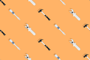 Tools seamless pattern. Tools: construction brushes, hammer, wrench on an orange background.