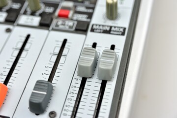 Close-up of two gray faders on a mixing console.