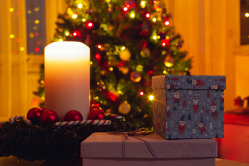 Christmas eve concept. Burning candle, gift box and festive lights.