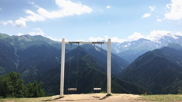 Slow motion static view of swinging iconic Mestia swings in Heshkili Huts Svaneti wth background of caucasus mountains