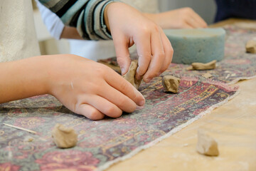 A child molds a product from clay in a modeling lesson.