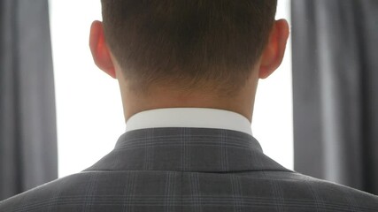 A young man put on his tuxedo jacket. Groom dresses for an event or wedding.