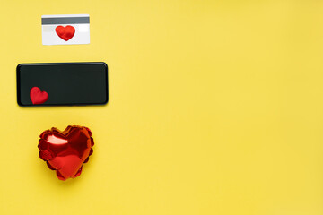 Valentine's Day background with mobile smart phone,credit card,red Heart on pastel yellow background