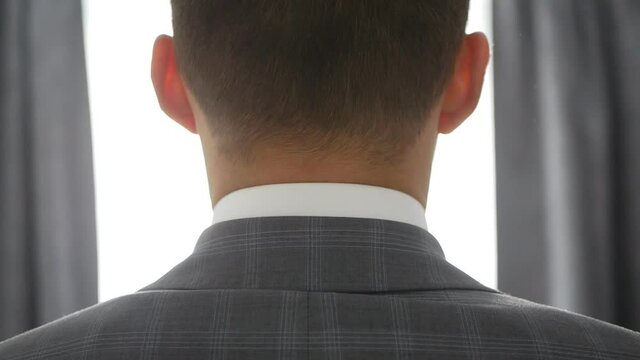 A young man put on his tuxedo jacket. Groom dresses for an event or wedding.