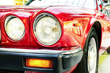 A closeup of the headlight and front bumper on a vintage car.