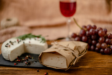 Goat cheese, grapes and wine lie on a wooden table. Cheese at home.