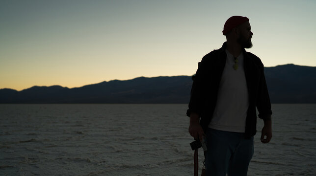 Unrecognizable male traveler with photo camera standing in empty terrain