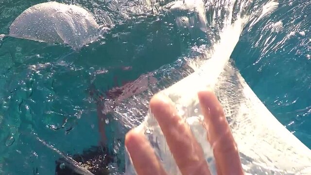 mano atrapada en el pl&aacute;stico por la contaminaci&oacute;n y el cambio clim&aacute;tico