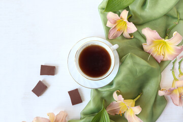A cup of fragrant tea with chocolate pieces, a light scarf, the color of a pink daylily on a light background, a place for text