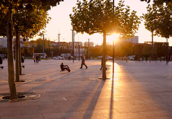 young people ride on an electric scooter in a city park at sunset. Russia, Krasnodar, 2020/11/08