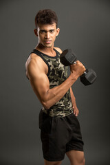 Plakat muscular young man lifting weights for biceps curl on dark background.