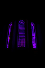 Purple backlit stained glass of dark church at night
