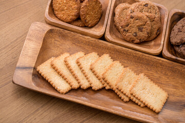 wooden tray with many different types of cookies on wooden background.