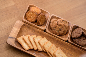 wooden tray with many different types of cookies on wooden background.