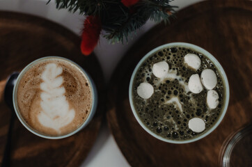 Cup of coffee and matcha with marshmallows on a wooden table with Christmas motifs