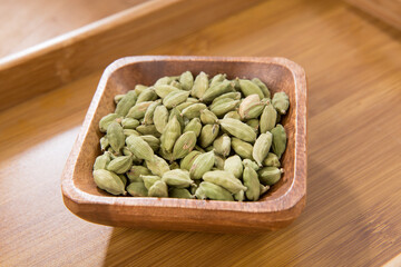 Bowl of cardamom on wooden tray   