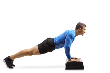 Muscular man exercising push-ups on a step aerobic platform