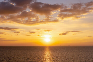 Fototapeta premium Sunset reflection ocean. beautiful sunset behind the clouds and blue sky above the over ocean landscape background