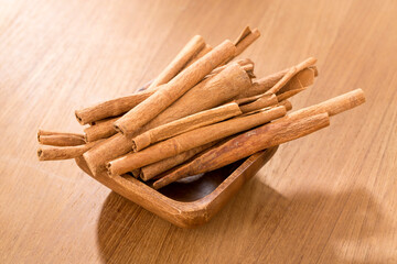 Bowl with cinnamon sticks on wooden table.