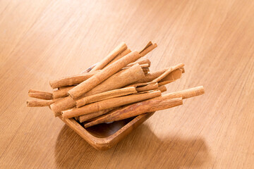 Bowl with cinnamon sticks on wooden table.
