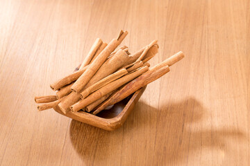 Bowl with cinnamon sticks on wooden table.