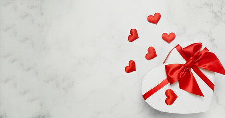 Valentine's Day background. Gift box in the form of a heart with a red bow on a white table. International womens day, 8 march, birthday, wedding, love concept. Flat lay, top view, copy space