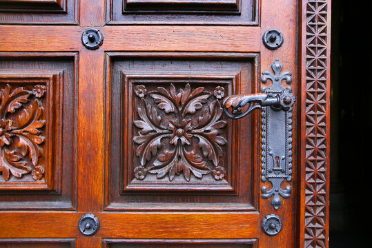 Close-up of vintage wooden hand-carved door with metal handle