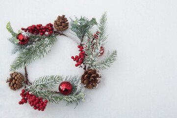 Christmas wreath with red berries and pine cones on the snow