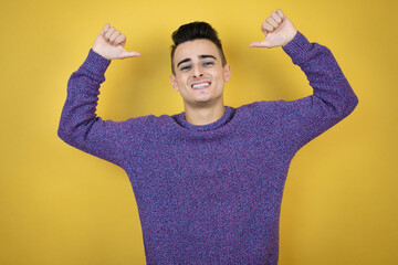 Young caucasian man over isolated yellow background looking confident with smile on face, pointing...