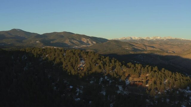 beautiful aerial clip of the sunrise on a mountain landscape with pine trees and snow