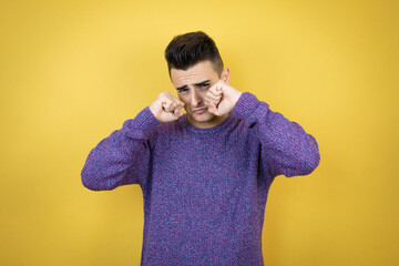 Young caucasian man over isolated yellow background depressed and worry for distress, crying angry and afraid. Sad expression.