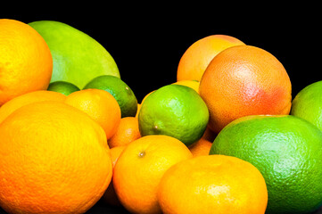 Isolated vibrant citruses on black background. Oranges, tangerines, limes, pummelo, grapefruits.