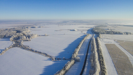 Fototapeta na wymiar Winter road along the fields between cities aerial view from a drone. Winter road view from a drone